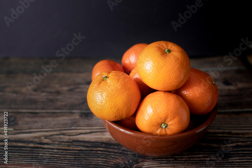 Plate with juicy tangerines on table and wooden background
