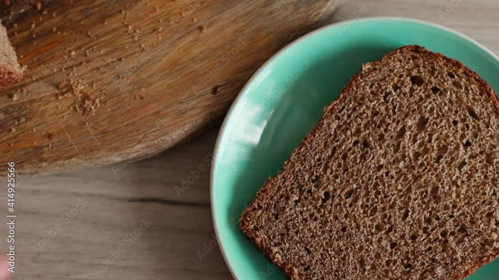Person spreading cream cheese on piece of bread. Yeast-free rye bread with seeds. Preparing breakfast on a wooden table Person spreading cream cheese on piece of bread. Yeast-free rye bread with seeds. Preparing breakfast on a wooden table