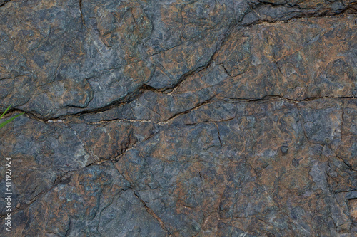The surface of an old rock with cracks and moss. Old rock texture (wild background)
