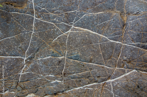 The surface of an old rock with cracks and moss. Old rock texture (wild background)

