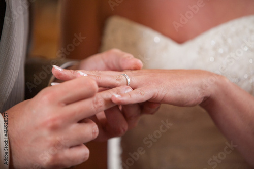 Closeup of bride putting a wedding ring onto the groom's finger. Couple exchanging wedding rings. High quality photo