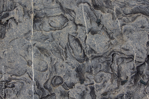 The surface of an old rock with cracks and moss. Old rock texture (wild background)
