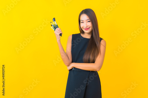 Portrait beautiful young asian business woman with make up brush