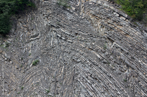 The surface of an old rock with cracks and moss. Old rock texture (wild background)
