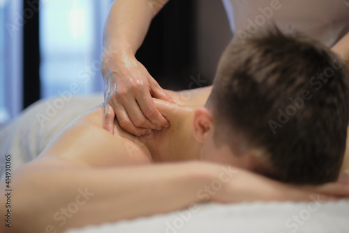 Close-up of man enjoying in relaxing shoulders massage . Man relaxing on massage table receiving massage