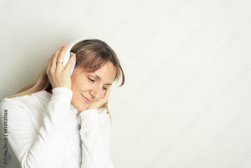 Portrait of smiling pretty woman enjoying music with white headphones on white background Portrait of smiling pretty woman enjoying music with white headphones on white background