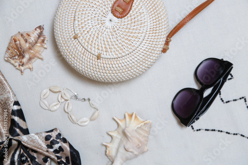 Summer fashion accessories on white. Rattan bag, black sunglasses and silk scarf.