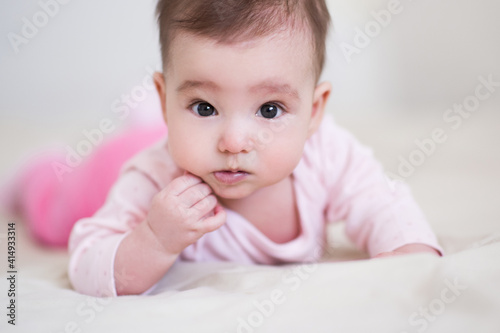 Cute baby under 1 year old wearing pajamas crawling in bed at home close up. Childhood. Good morning. Healthy lifestyle. Looking at camera.