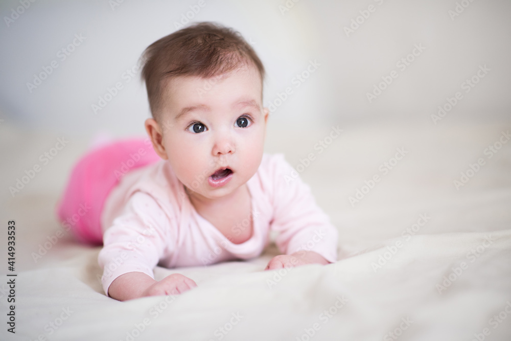 Cute baby under 1 year old with surprised expression wearing pajamas crawling in bed at home close up. Childhood. Good morning. Healthy lifestyle.