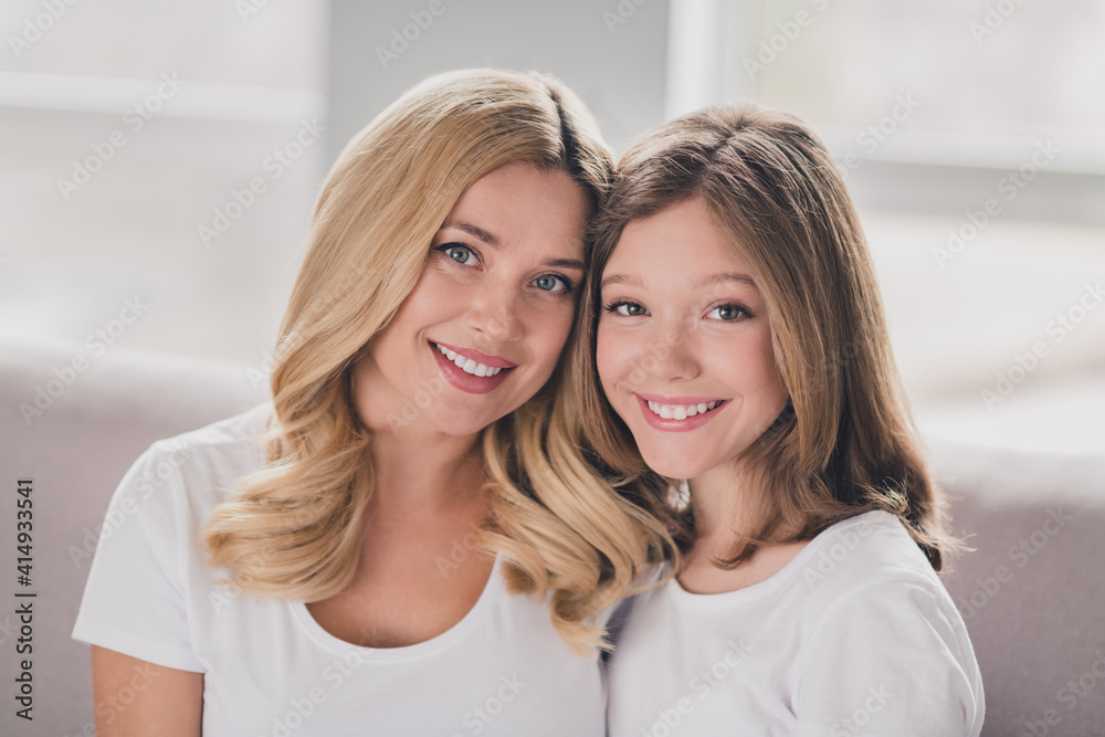Photo of sweet charming mommy daughter wear white t-shirts smiling hugging sitting couch inside indoors home room Photo of sweet charming mommy daughter wear white t-shirts smiling hugging sitting couch inside indoors home room
