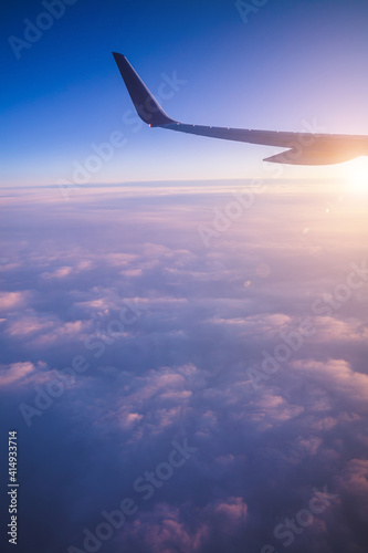 Top view from inside window airplane of a sunset sky and wing