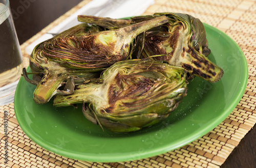 cooked fried halves artichokes on green plate