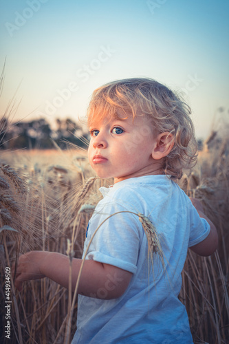 Little beautiful child looks over the wheat field