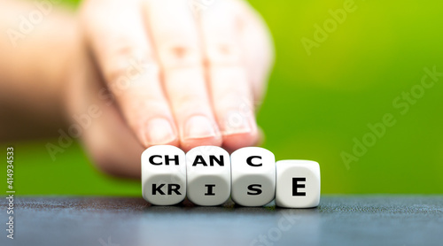 Hand turns dice and changes the German word "Krise" (crisis) to "Chance" (chance).