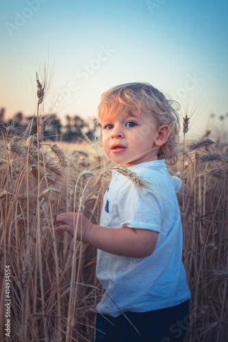 Little beautiful child looks over the camera in a wheat field