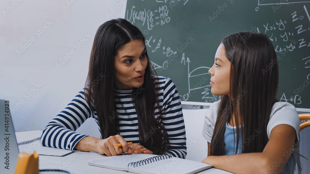 mother and daughter looking at each other while doing homework mother and daughter looking at each other while doing homework