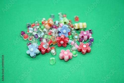 Colored beads for making a bracelet on a green background.