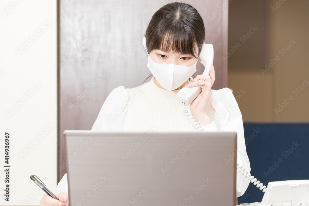 Woman in a mask making a work call on a landline