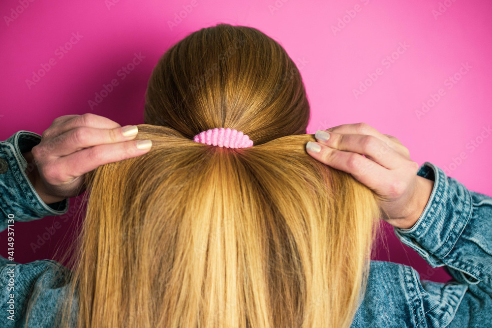 Girl doing her hair with a pink hair tie Girl doing her hair with a pink hair tie