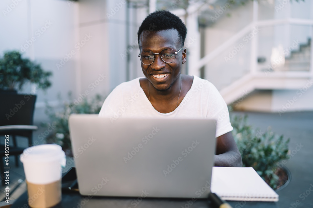 Happy young man using laptop in park cafe Happy young man using laptop in park cafe