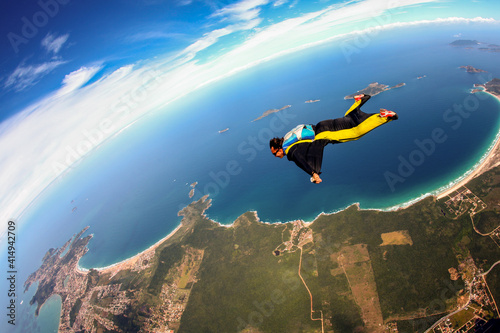 Fototapeta Skydiving wing suit flying over Brazilian beach
