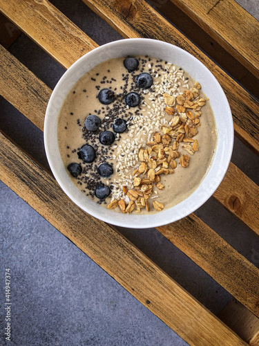 smoothiebowl with chia seeds, blueberry and granola on a wooden box photo