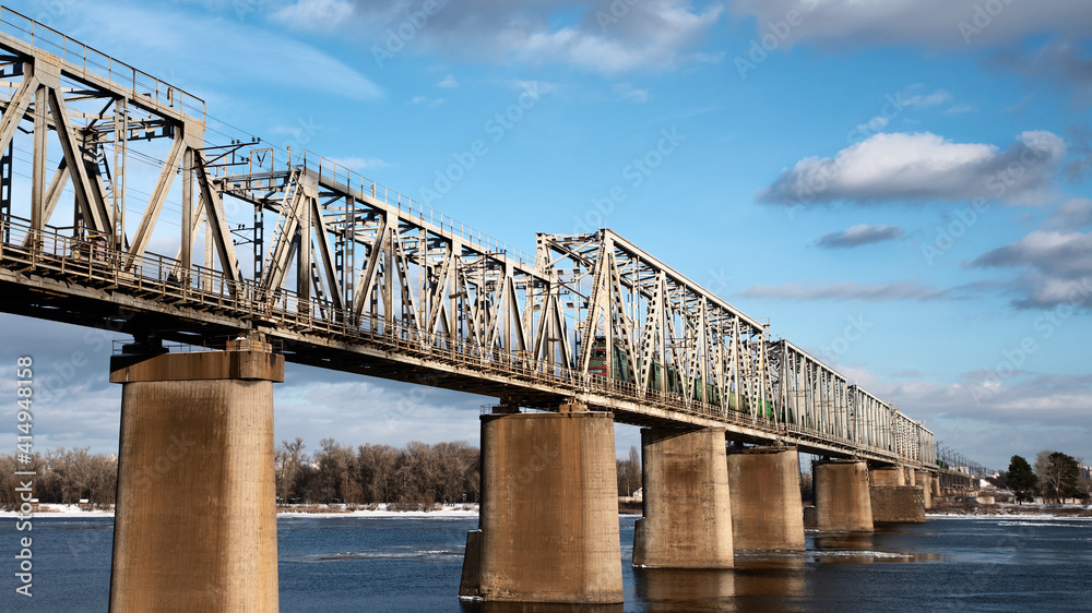 Fototapeta premium The train on the railway bridge against the blue sky.