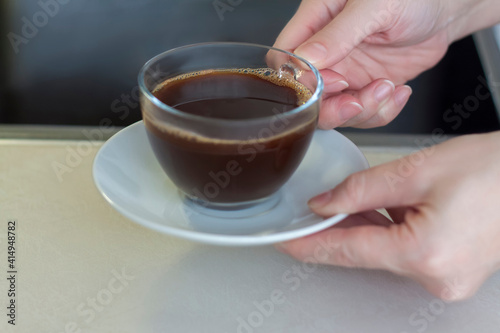 Women's hands hold a cup of coffee over the table. Breakfast with coffee. Make coffee in a turk.