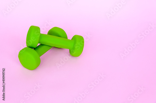 Green dumbbells for sports on a pink background. Sports, sports nutrition, healthy eating, diet. Space for the text.