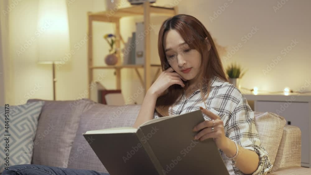 attractive Chinese lady is relaxing on sofa at home and enjoying reading with concentration on a tranquil night. attractive Chinese lady is relaxing on sofa at home and enjoying reading with concentration on a tranquil night.
