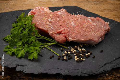 Raw beef steak with parley and salt on a serving black stone , Can be used as a background