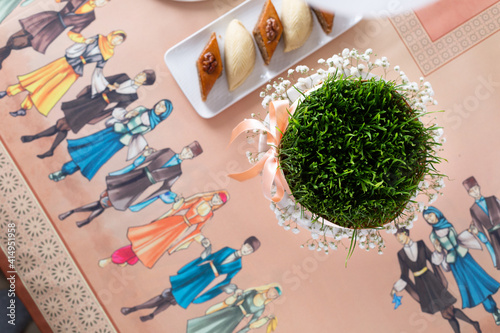 Beautiful Novruz table set up in pastel colors with wheat grass - semeni, satin ribbon, traditional pastry. National holiday, celebration of spring equinox