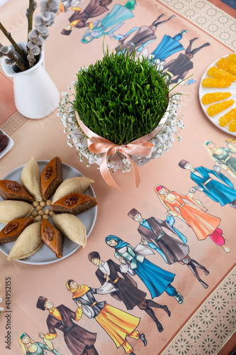 Beautiful Novruz table set up in pastel colors with wheat grass - semeni, satin ribbon, traditional pastry. National holiday, celebration of spring equinox