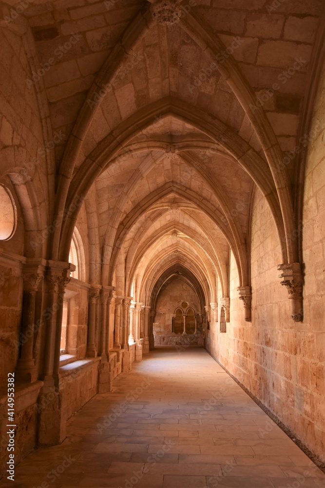 View into a hallway of the Cistercian Gothic Claustro de los Caballeros cloister with its pointed arches in yellow pink sandstone at the Trappist Monasterio de Santa María de Huerta monastery, Spain
