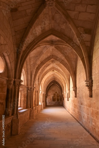 View into a hallway of the Cistercian Gothic Claustro de los Caballeros cloister with its pointed arches in yellow pink sandstone at the Trappist Monasterio de Santa Mar  a de Huerta monastery  Spain