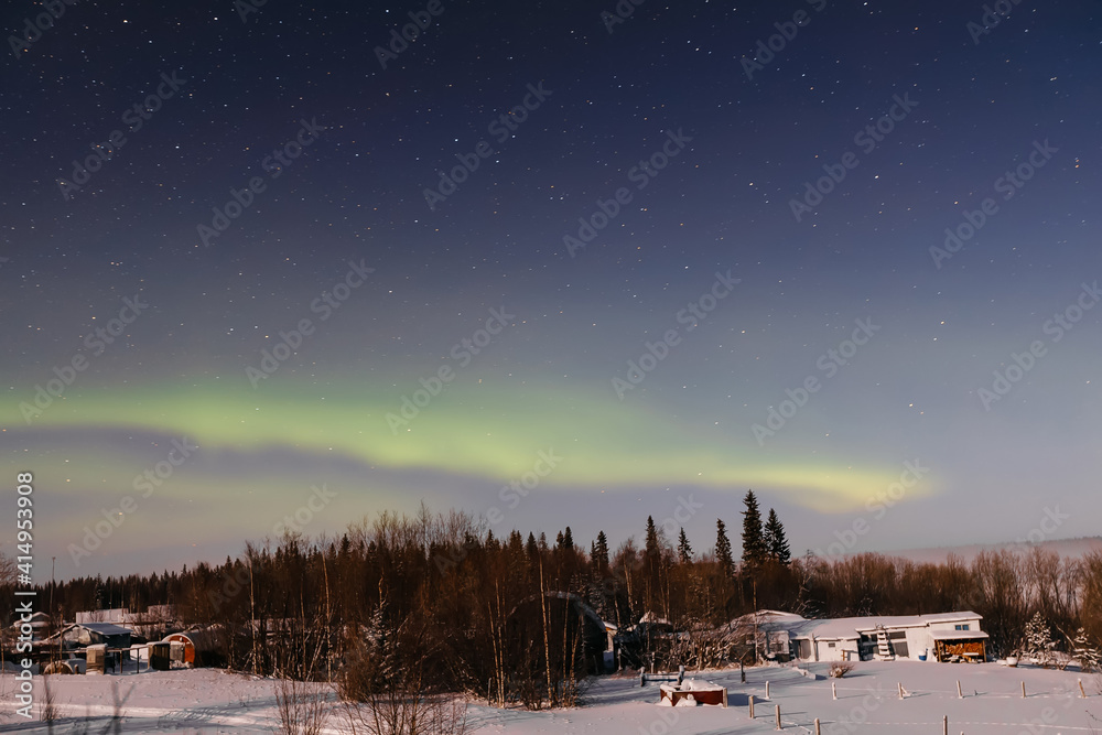 Northern Lights in the starry sky above the village. Night landscape