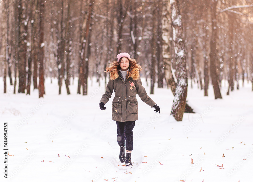 Young beautiful girl runs through the snow in the park in winter