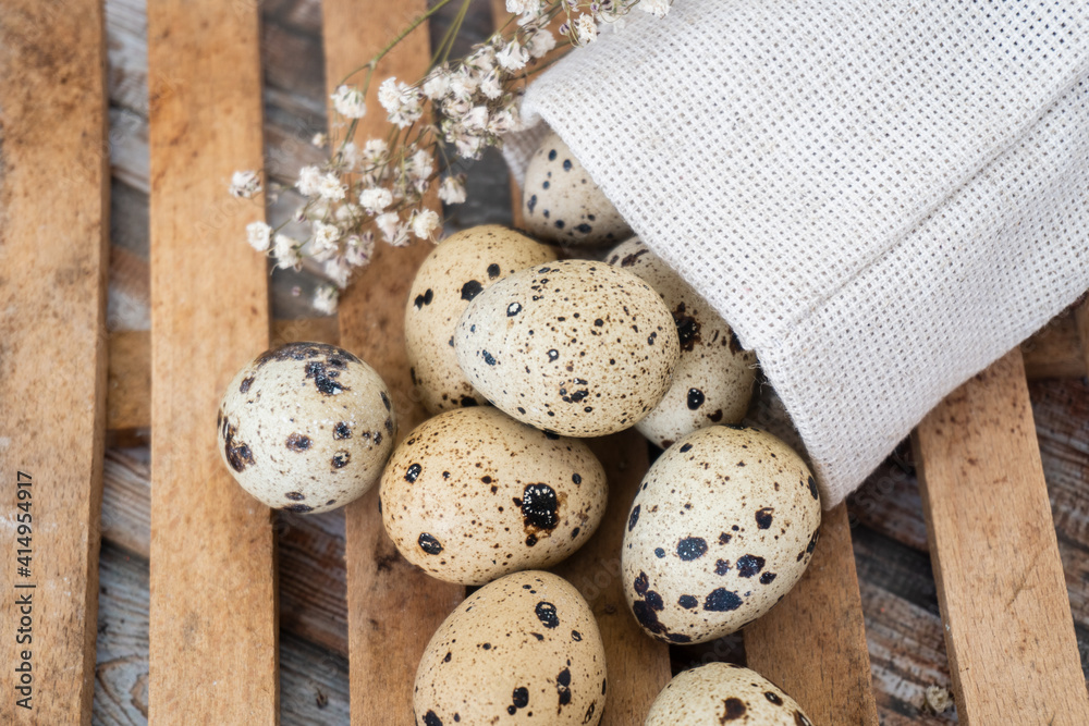 organic farmer quail eggs in burlap sack over old wooden background, selective focus. Rustic style