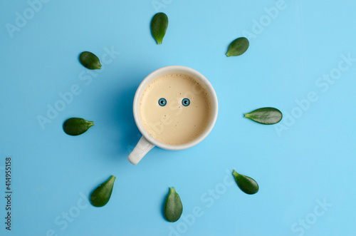 morning cup of coffee on a blue background with leaves around it