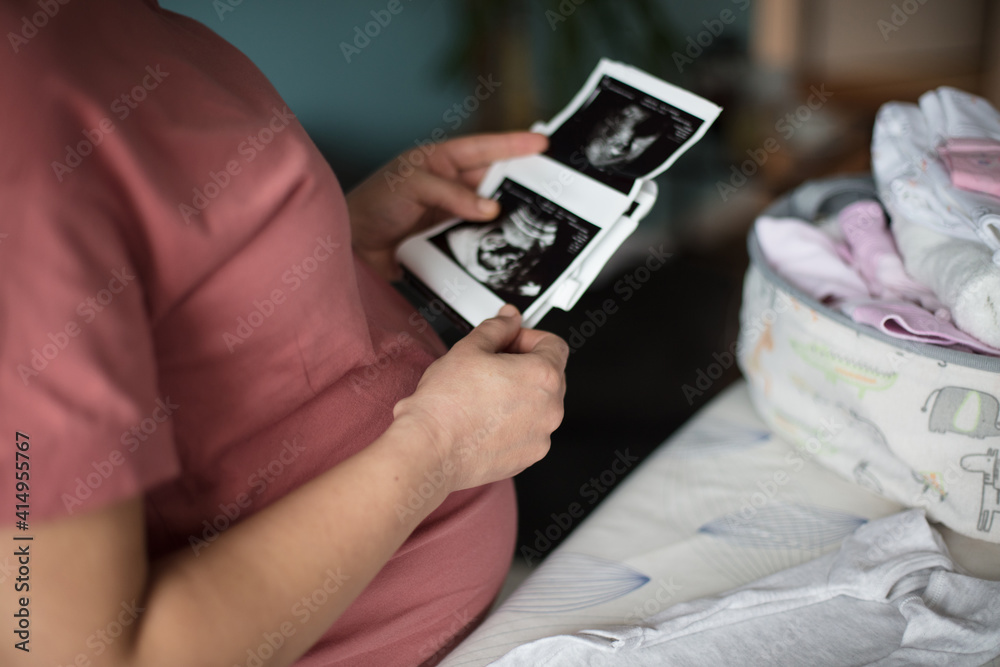 Pregnant woman holding a sonogram of her unborn baby.