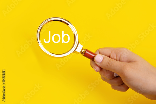 hand holding magnifier over yellow background, search job concept