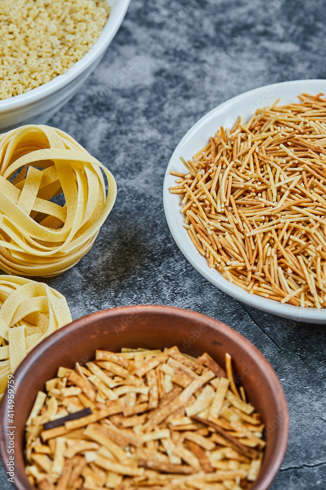 Various types of dry pasta on the marble background