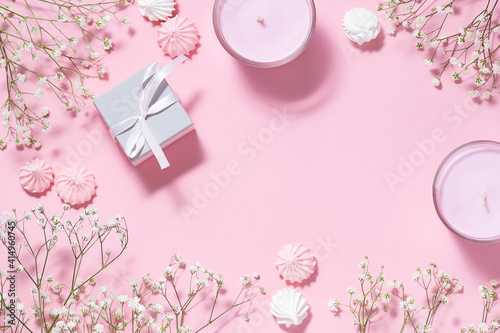 Beautiful spring festive frame made with flowers, merengue cookies and aromatic candles on pink pastel background with copy space for your text. Women’s Day, Mother’s Day concept.