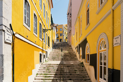 Staircase alley in the old town of Lisbon with yellow picturesque house facades.