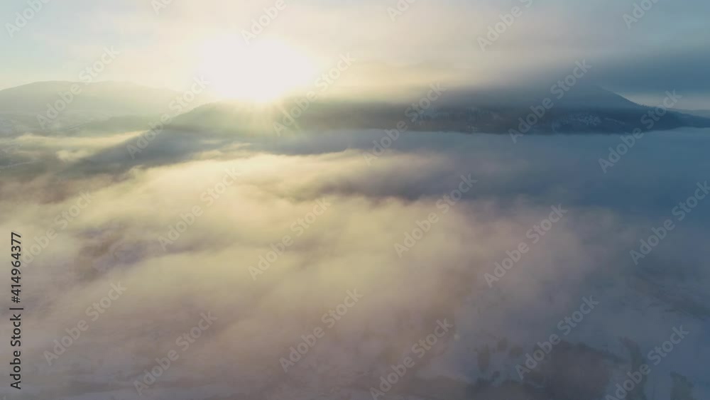 Epic Aerial Flight Over Clouds Sunrise Colorful Winter Golden Hour Sunset Colors. Flying on a winter day in the sun among low clouds over the mountain village. Epic Aerial Flight Over Clouds Sunrise Colorful Winter Golden Hour Sunset Colors. Flying on a winter day in the sun among low clouds over the mountain village.