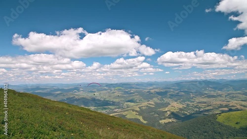 Delightful flight of paragliders over mountain peaks