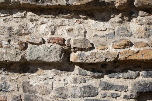 Brick gray wall with embossed rocks, strong light