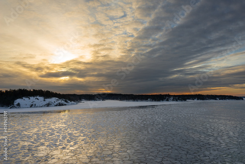 Sunset. Beautiful view of the northern snow covered shores of Scandinavia  Baltic sea at sunset time in winter. Amazing sky bright colors and clouds on the horizon. Winter landscape. 