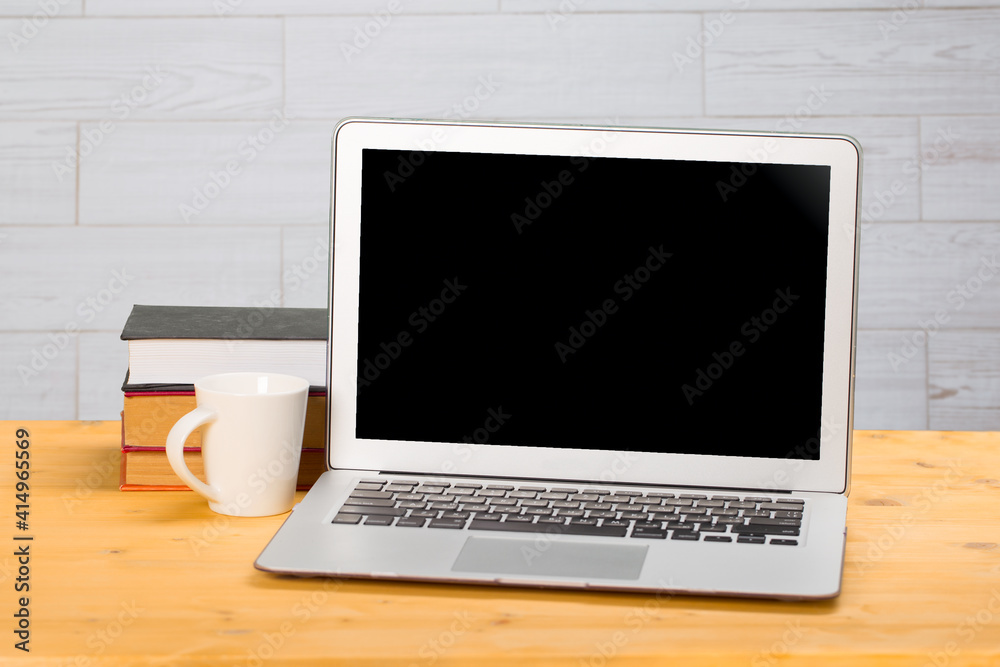Laptop with blank screen, cup of coffee and books or notebooks on a wooden table. mockup for your text Laptop with blank screen, cup of coffee and books or notebooks on a wooden table. mockup for your text