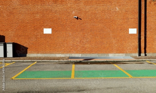 Brick wall with surveillance camera and two blank signboard. Sidewalk,reserved parking and asphalt road in front. Background for copy space  photo